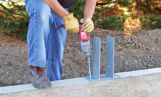Construction worker installing Sturi-Wall® bracket with drill on concrete foundation